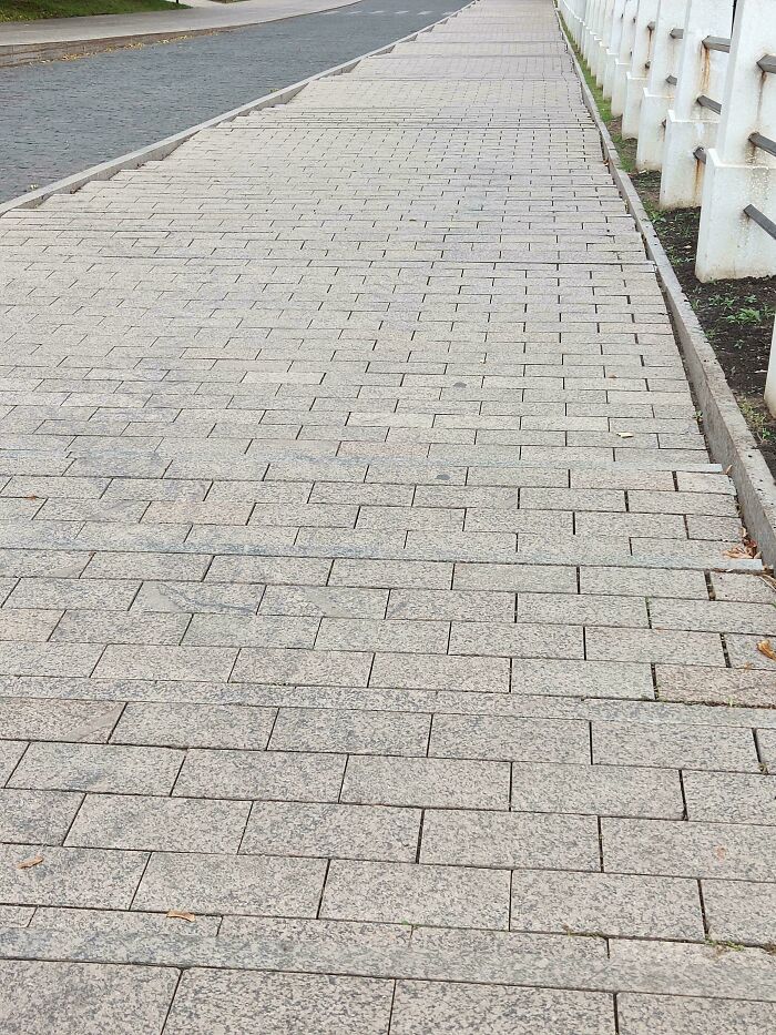 Sidewalk with uneven brick pavement showing a poor design decision causing an unexpected walking hazard.