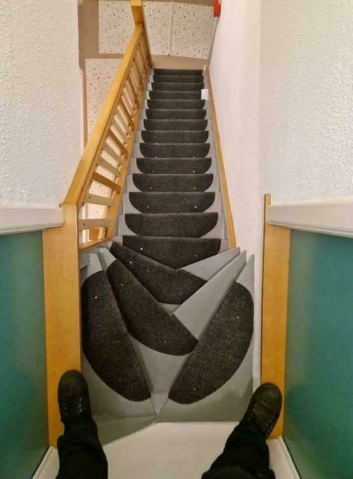Worn stairs with confusing carpet design creating a visual problem, showcasing dumb design decisions by designers.