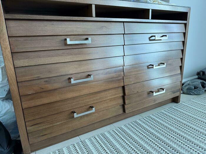 Wooden dresser with misaligned drawers showing poor design mistakes causing usability problems.