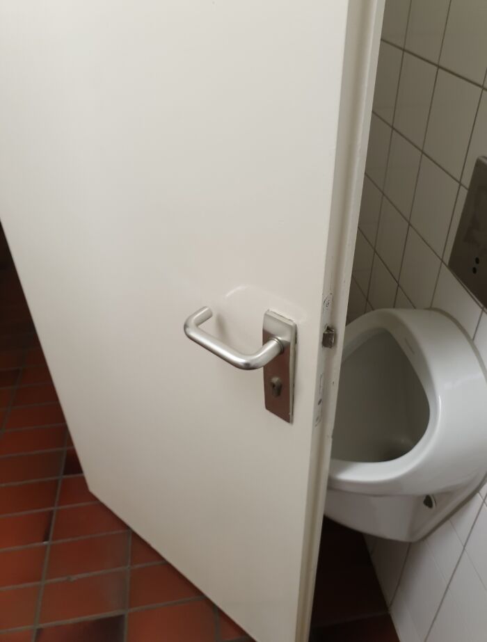 Poor bathroom stall design showing urinal blocked by door, an example of dumb decisions and design problems nobody asked for.