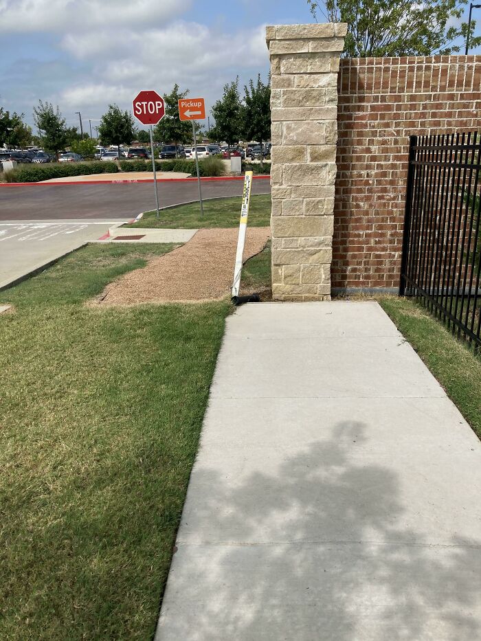 Sidewalk abruptly ending at a brick wall showing dumb design decisions causing problems for pedestrians and accessibility.