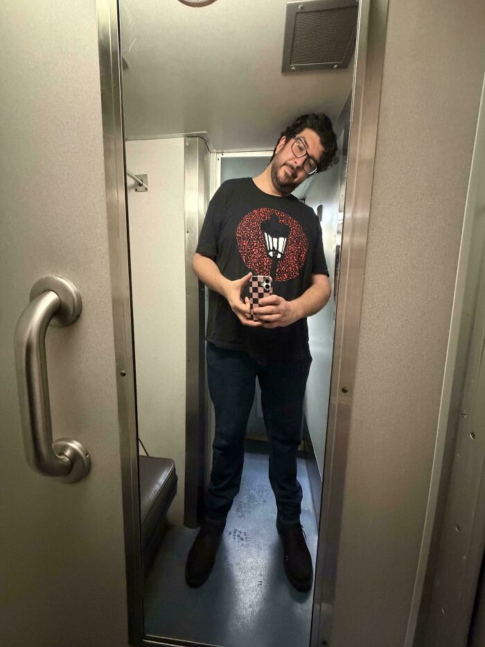 Tall person taking a selfie inside a narrow room, illustrating common struggles only tall people face in small spaces.