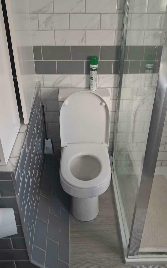 Small bathroom design with poorly placed toilet next to a glass shower, an example of dumb design decisions creating problems.