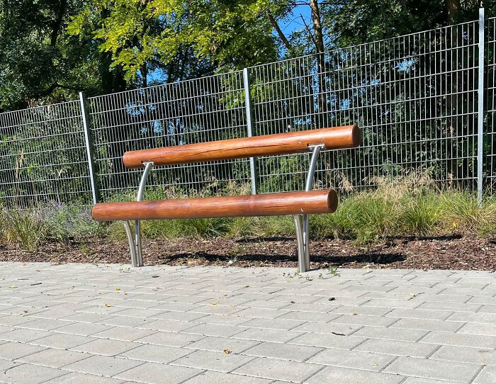 Outdoor bench with wooden logs and metal supports showing a dumb design decision creating an unusable seating problem.
