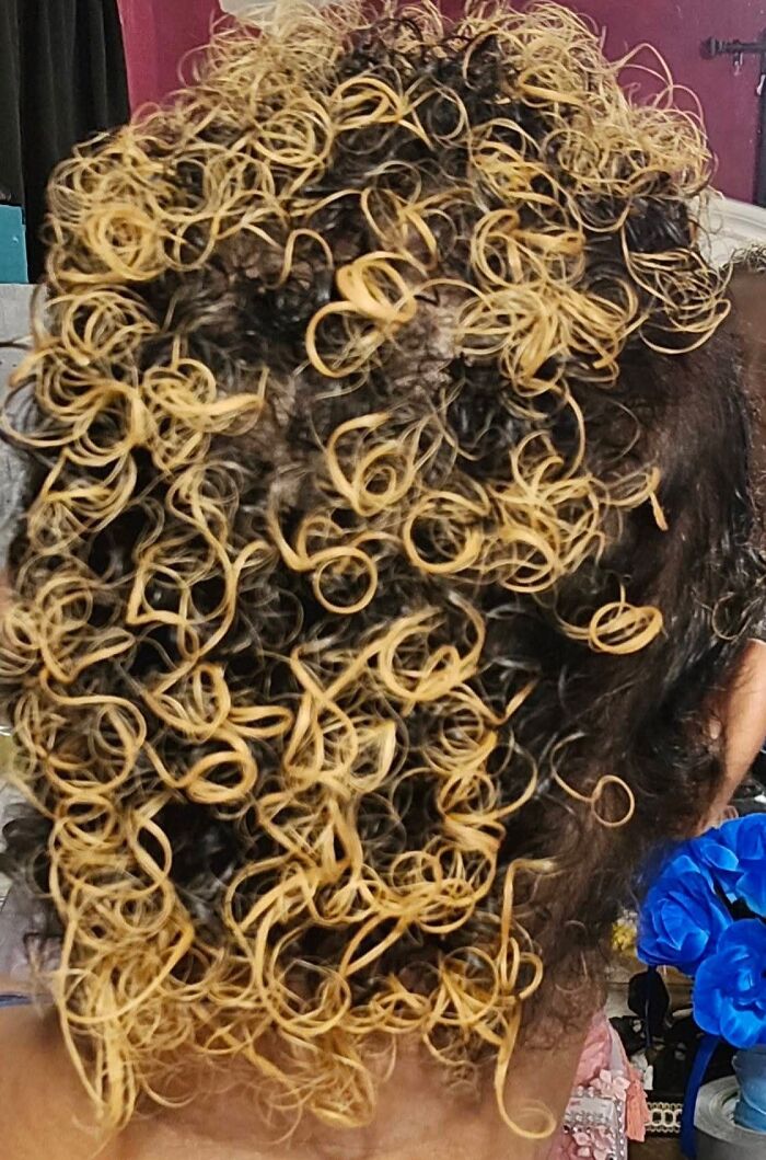 Tightly curled hair dyed unevenly blonde and black, showcasing one of the most disastrous hairstyles on an individual.