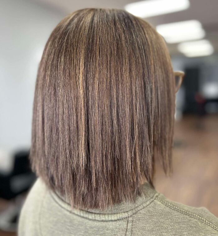 Back view of a straight, uneven brown hairstyle in a salon setting, showcasing one of the disastrous hairstyles.