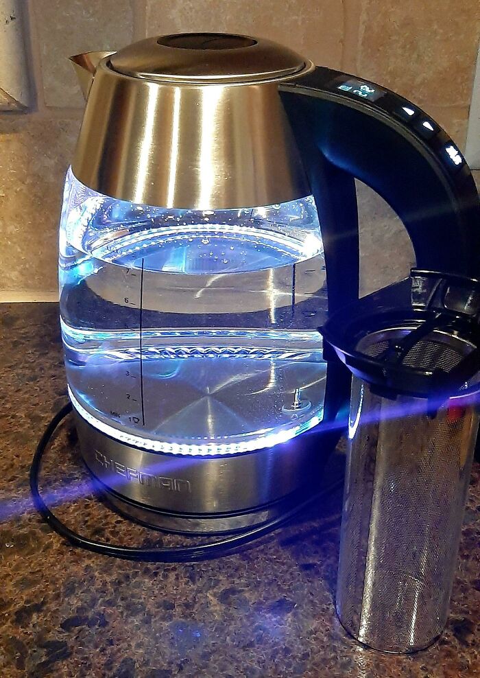 Electric kettle with blue LED light heating water on kitchen counter, a normal practice in Europe some US may find weird.