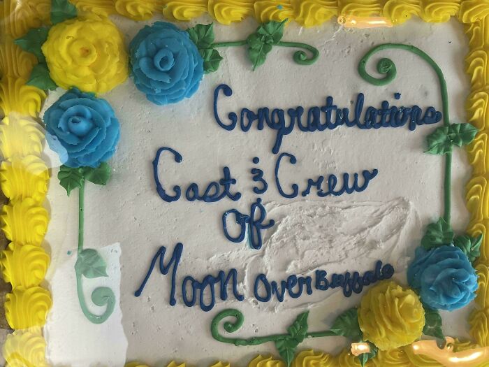 Cake decorated with yellow and blue flowers and a congratulatory message for a cast and crew, funny cakes reflecting honest emotions.