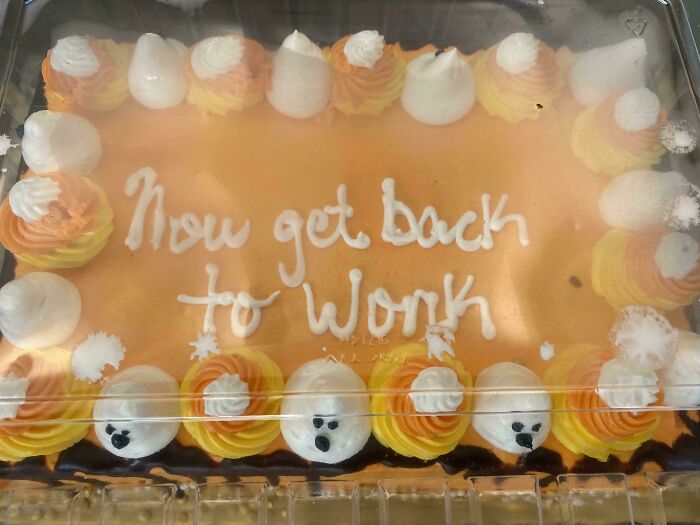 Funny cake with orange and white frosting and the message Now get back to work, reflecting honest emotions.