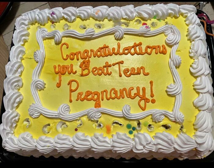 Cake with yellow icing and white frosting border, featuring humorous text celebrating beating teen pregnancy.