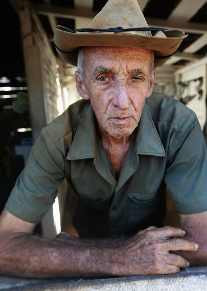 Elderly man in a hat leaning forward, reflecting a moment of contemplation about family secrets and personal stories.
