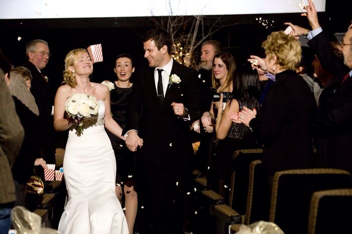 Bride and groom walking down the aisle smiling as guests throw confetti in this awkward wedding photo moment.