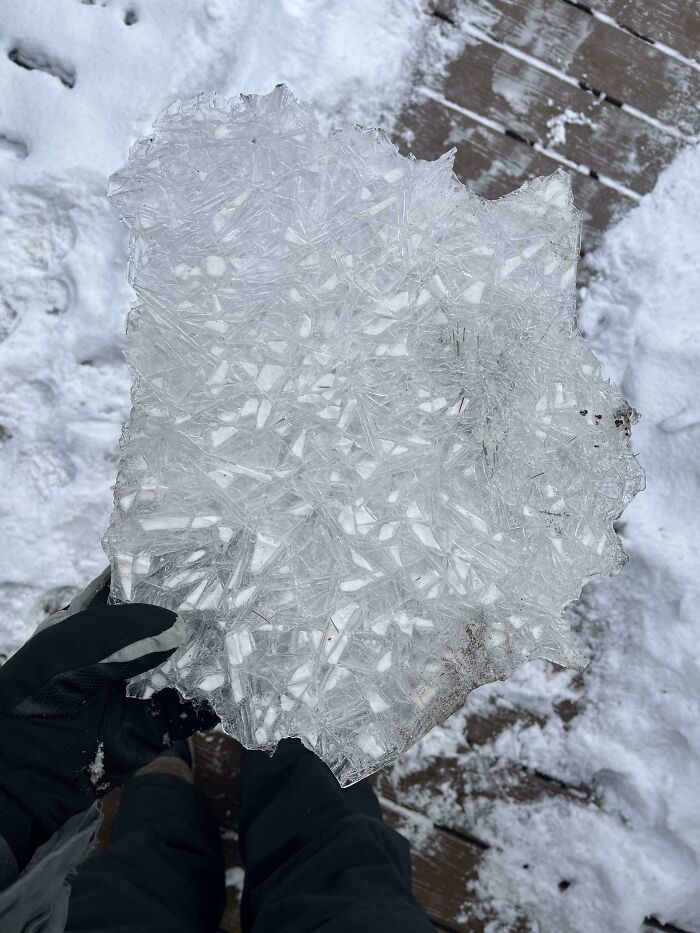 Person holding a large piece of c*****d ice outdoors in snowy winter, showcasing cozy winter images without stepping into the cold.