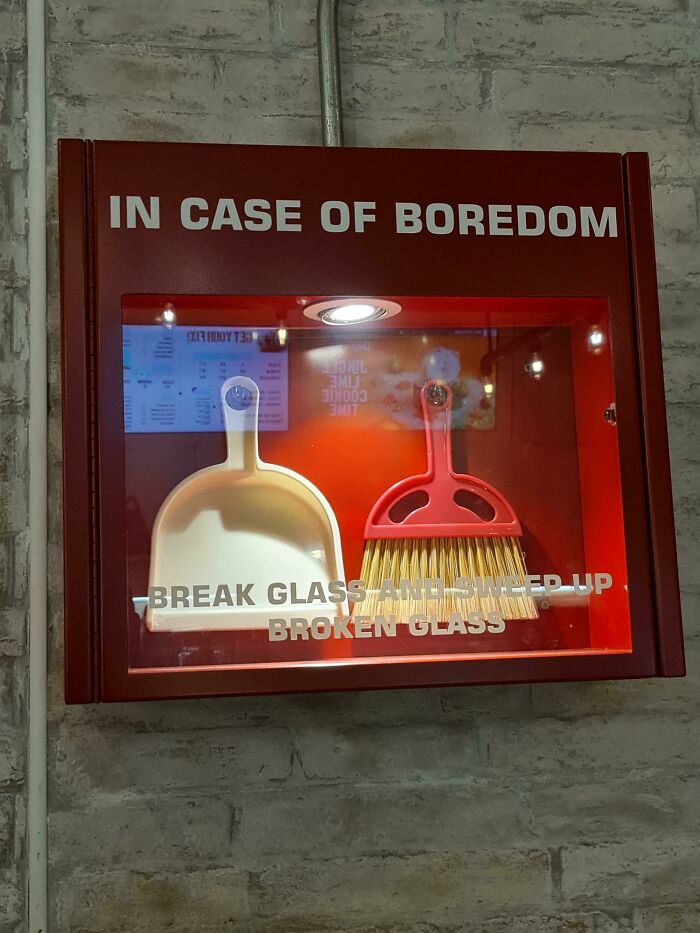 Red emergency box labeled in case of boredom containing dustpan and small broom, a confusing picture with funny appeal.