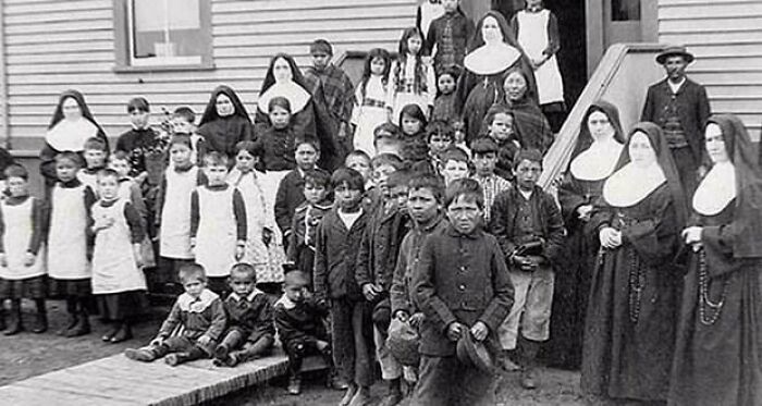 Black and white photo of children and nuns outside a building, illustrating unsettling history and crime stories.
