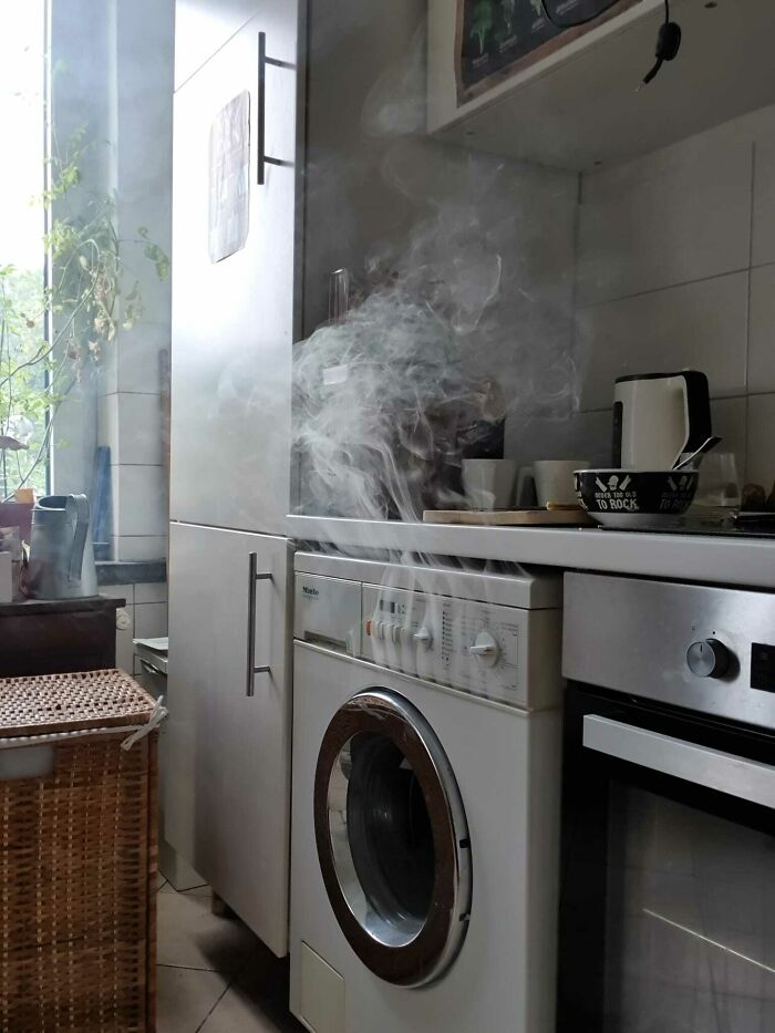 Steam rising from a washing machine in a compact European kitchen showing normal practices that may seem weird to the US.