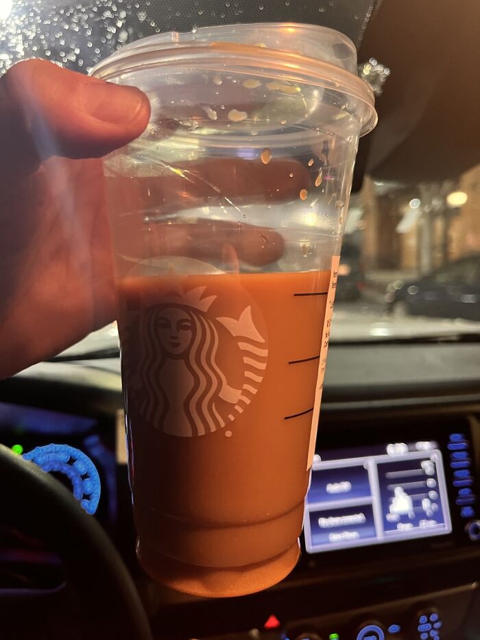 Hand holding a Starbucks cup with iced coffee inside a car, illustrating normal practices in Europe US may find weird.