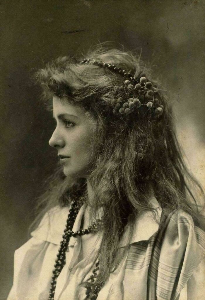 Victorian era portrait of a woman with long hair adorned with beads, showcasing fashion from a different time period.