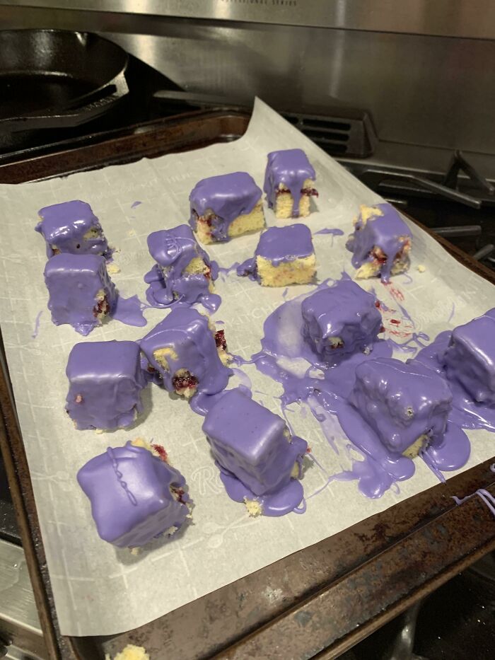 Chunks of dessert on parchment paper with uneven purple icing melted and dripping, showing a ruined dessert attempt.