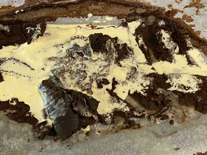 Dessert ruined with melted ice cream and broken chocolate cake pieces in a messy baking pan.