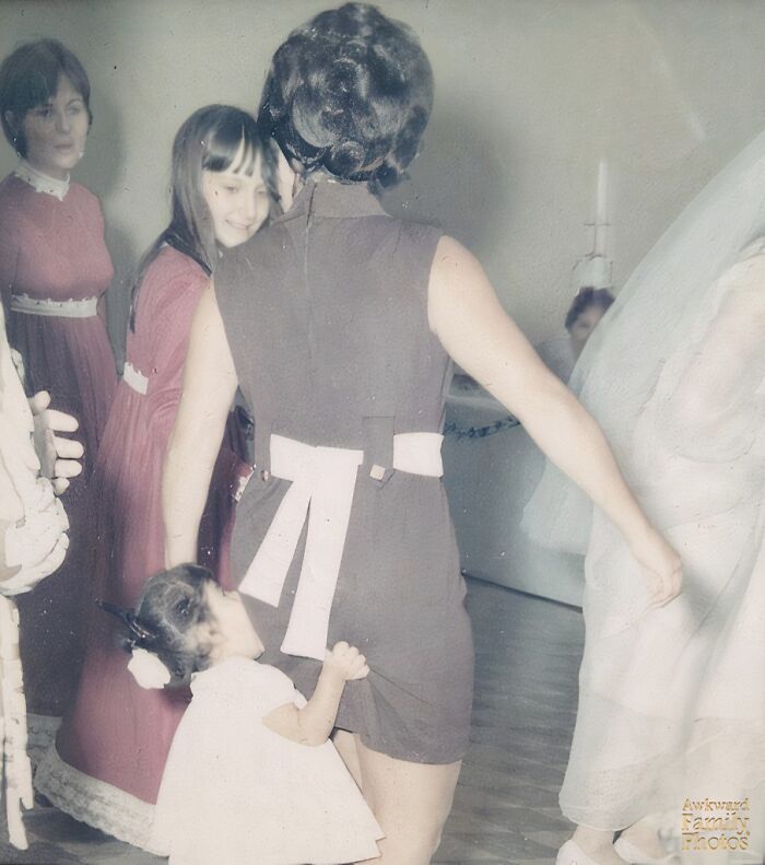 Little girl awkwardly grabbing woman’s dress at a wedding, capturing one of the most awkward wedding photos moments.