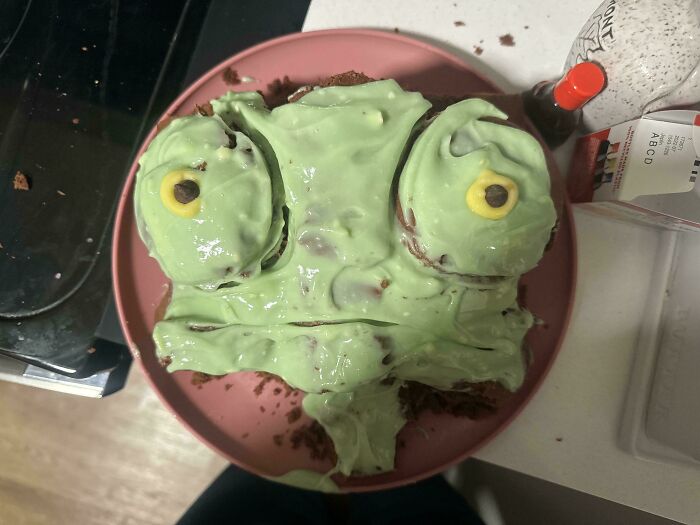 Failed dessert with green frosting and candy eyes resembling a distorted face, an example of ruined dessert attempts.