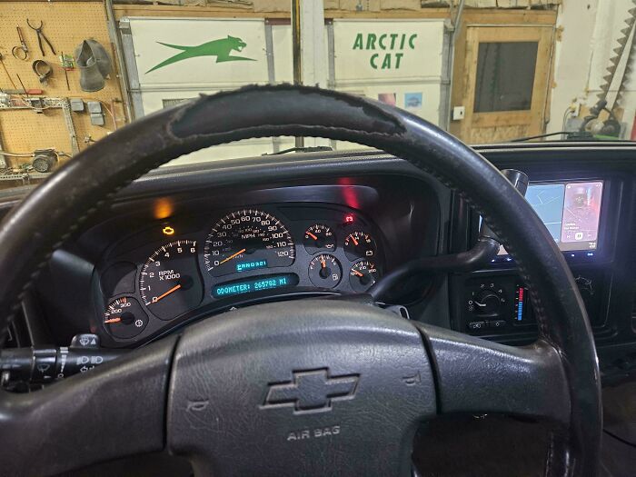 Worn down steering wheel and dashboard of an older Chevrolet inside a garage setting.
