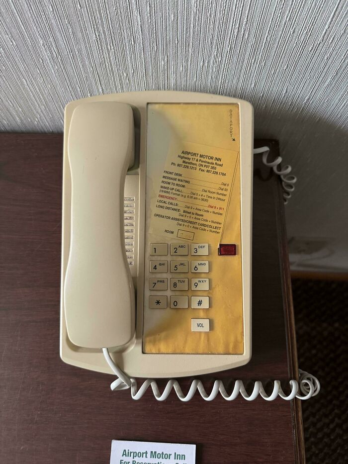 Worn down hotel phone with faded buttons and yellowed surface showing everyday object wear over time.