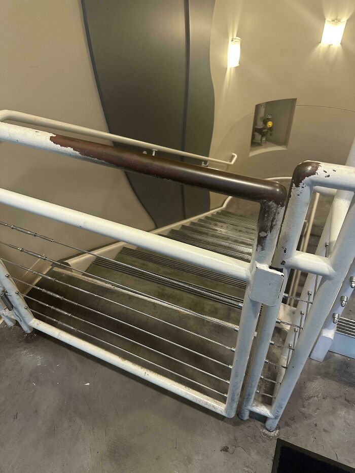 Worn down handrail and gate in a stairwell showing everyday objects with unexpected wear and tear patterns.