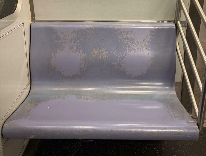 Worn down subway plastic seat showing faded colors and scratches from everyday use over time.