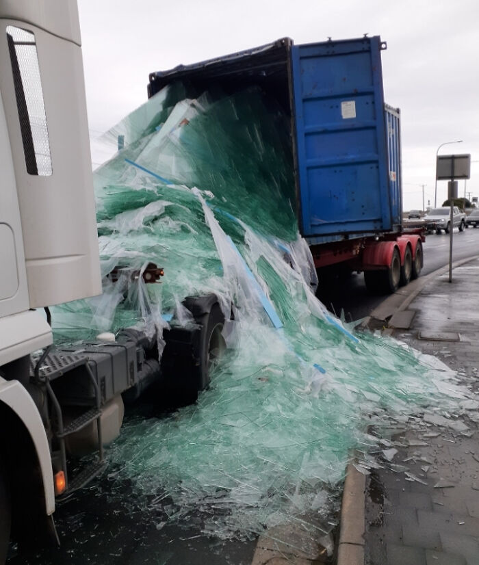 Broken glass spill from a truck accident causing an expensive and unfortunate fail on a rainy roadside.