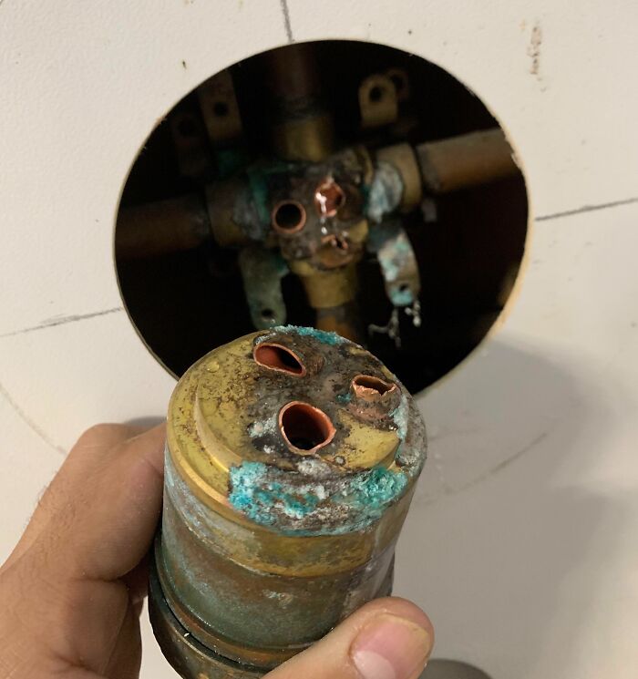 Corroded and damaged plumbing valve held in hand, showcasing an unfortunate and expensive fail in home repair.