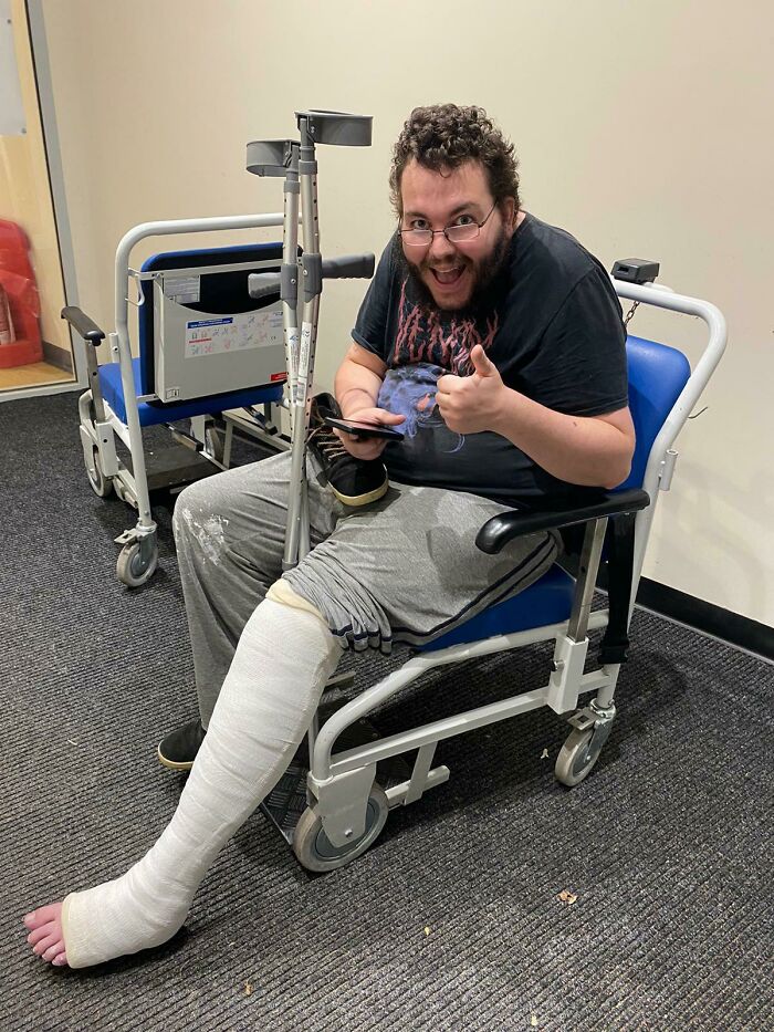 Man with a full leg cast sitting in a wheelchair giving a thumbs up after an unfortunate and expensive fail accident.