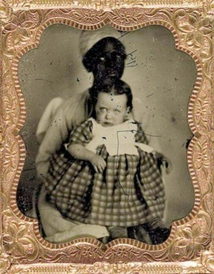 Victorian era photo of a child sitting on a woman's lap, showcasing unique and eerie vintage portrait style.