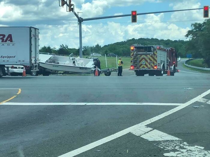 Truck hauling a boat stuck at a red light with fire truck and safety personnel at the scene, showcasing expensive fails.