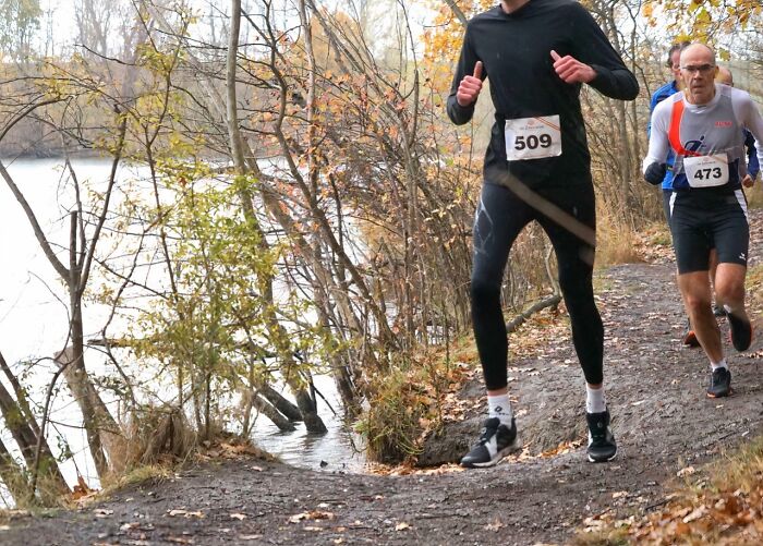 Two tall people running a trail race near a lake, highlighting common struggles only tall people face outdoors.