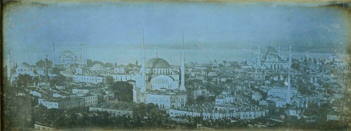 Panoramic historic site photo showing iconic domed buildings and ancient cityscape under a clear sky.