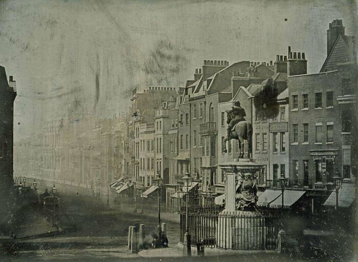 Historic site photo showing an old city street with historic buildings and an equestrian statue in the foreground.