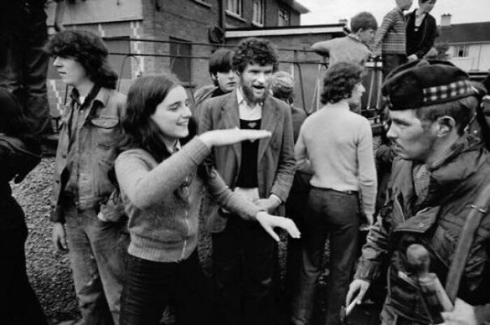 Black and white photo of young people interacting with a soldier at a historic site, capturing history repeated moments.