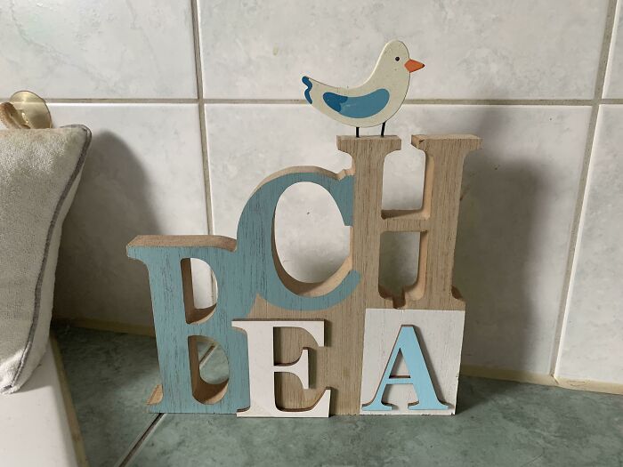 Wooden decorative letters arranged incorrectly with a small bird on top, showcasing designers' writing fails.