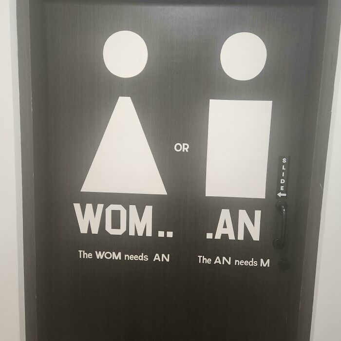 Bathroom door with a design fail showing incomplete WOMAN text, highlighting designers trying to write and failing miserably.