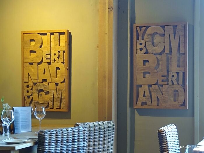Wooden wall art with jumbled letters in a restaurant setting illustrating designers failing to write correctly