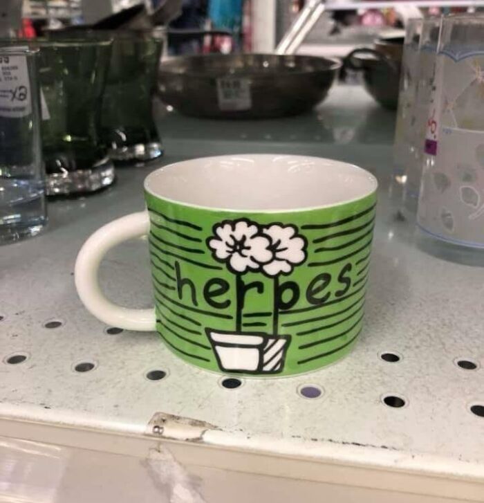 Green mug with a misspelled label herbes and a hand-drawn plant, showcasing designers' writing fails humorously.