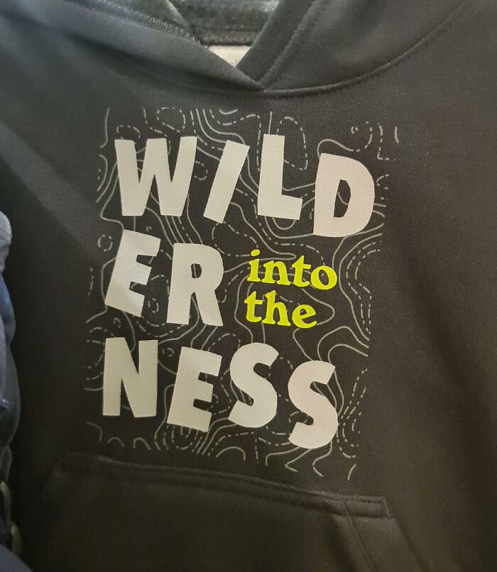 Black hoodie with a design displaying the phrase wild er ness with text placement errors, showcasing designer writing fails.