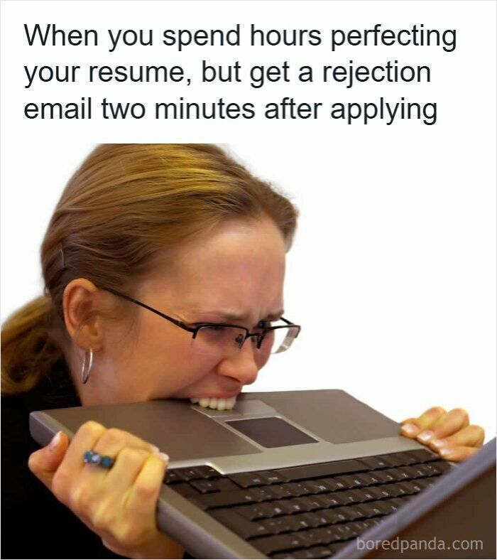Frustrated woman biting laptop in reaction to quick rejection after spending hours on her resume, depicting resume memes.