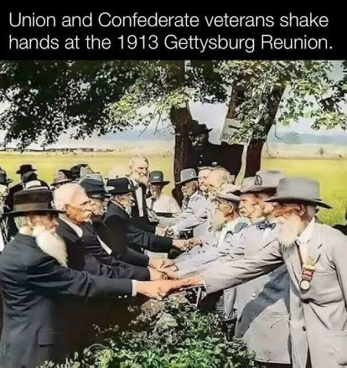 Union and Confederate veterans shaking hands at the 1913 Gettysburg Reunion in a historic US history photo.