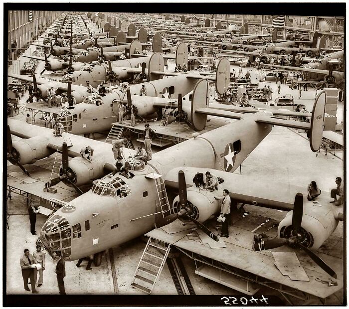 World War II era US military planes under assembly in a large factory, showing historical manufacturing and aviation history.