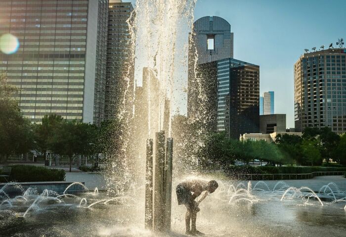 Person cooling off in an urban fountain captured in candid street photos showing life exactly as it happens.