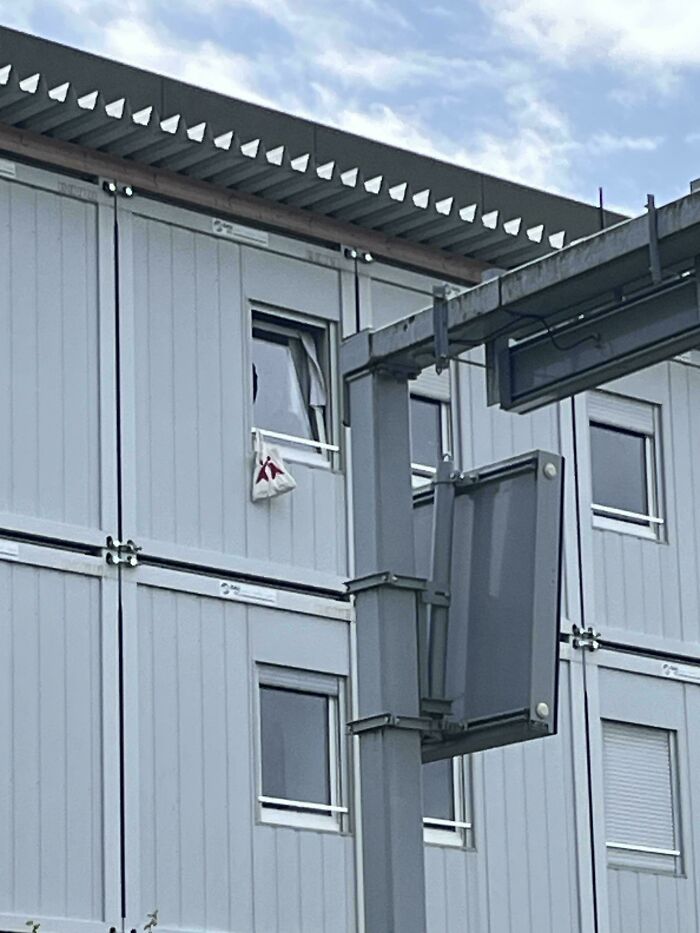 Gray modular classroom building with a broken window and an unusual object hanging outside, illustrating weird teacher behavior.