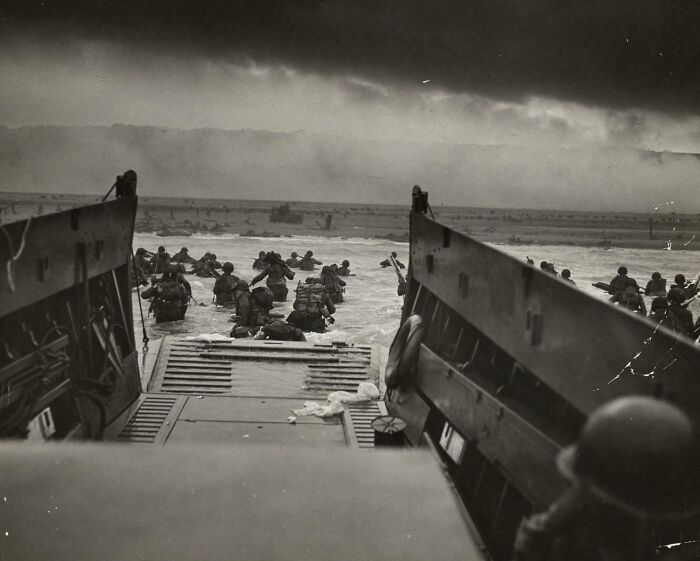 US history photo showing soldiers landing on a beach during a wartime amphibious a*****t in a historical battle scene.